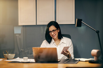 View through the glass of a businesswoman sitting at office using cutting edge technologies.