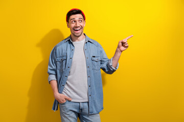 Photo of excited funky man dressed jeans shirt looking pointing finger empty space isolated yellow color background