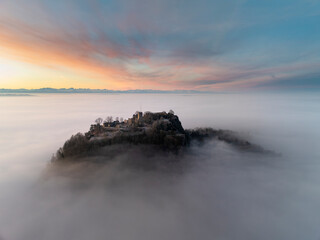 Luftbild vom Hegauvulkan Hohentwiel mit der oberen Festungsruine vor Sonnenaufgang, die bei einer Inversionswetterlage aus dem Nebel herausragt