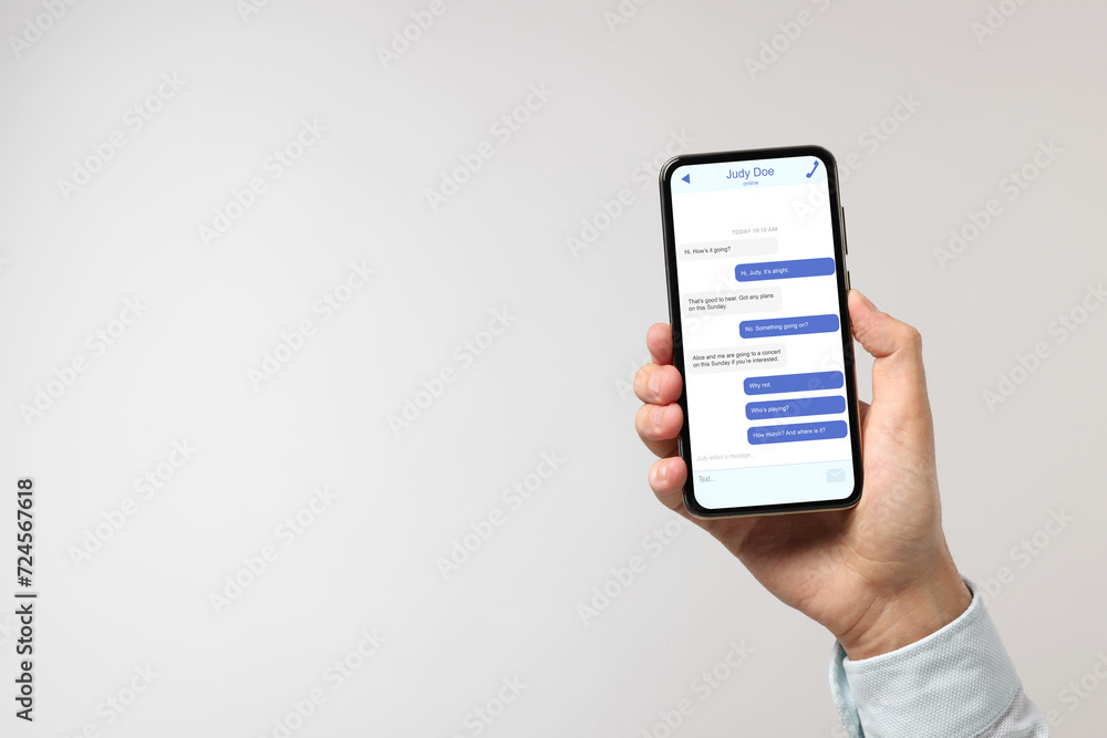 Poster man texting with friend using messaging application on smartphone against light grey background, clo