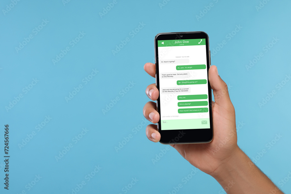 Poster man texting with friend using messaging application on smartphone against light blue background, clo