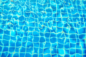 blue water wave pattern in swimming pool as the sun shines down during the day. Soft and selective focus. 
