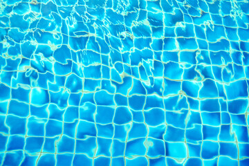 blue water wave pattern in swimming pool as the sun shines down during the day. Soft and selective...