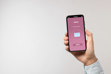 Got new message. Man holding smartphone on light grey background, closeup. Space for text
