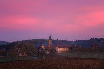 Pink and purple dawn breaking at sunrise over the rural village of Nabirat in the Dordogne region...