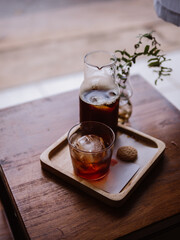 Pouring cold brew iced coffee in glass cup with ice cubes. Coffee In a glass bottle, Coffee drip, Hand holding a kettle drip coffee In the room, Black coffee in glass.