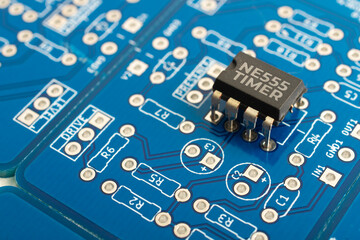 NE555 timer integrated circuit on a blue pcb - obrazy, fototapety, plakaty