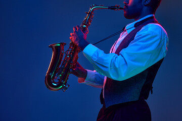 African-American jazz musician playing saxophone his major melodies against blue background in...
