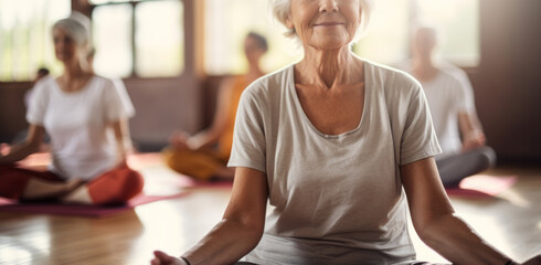 Portrait of elderly woman sits in the lotus position meditating in a yoga studio. Mental and spiritual health development at any age