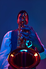 Close up portrait. African-American talented man, musician playing saxophone against studio...