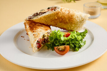 Grilled beef shawarma sandwich on a white plate, garnished with fresh lettuce and tomato. Suitable for fast food advertising and snack bar menus