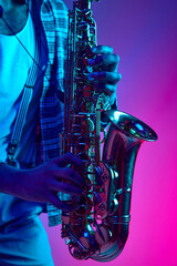 Close up photo of musician's hands playing jazz chord against pink-blue background in mixed neon...