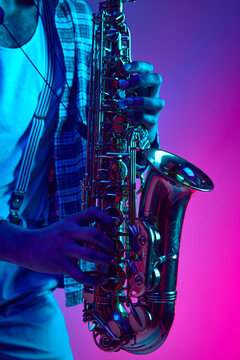 Close up photo of musician's hands playing jazz chord against pink-blue background in mixed neon light. Improvisation. Concept of classical musical instrument, concerts and festivals. Ad