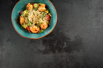 Top-down view of a vibrant shrimp and quinoa salad with avocado and tomatoes in a turquoise bowl