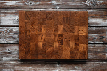 Empty oak cutting board on dark wooden background. Top view, flat lay. Culinary background for your design.