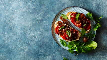 Healthy toasts with ripe tomatoes and arugula, top view. Copy space.