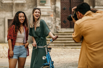 Three friends capturing memories in the cityscape, joyfully snapping photos of themself and...