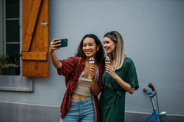 two friends, one Chinese and one Caucasian, sipping ice cream amidst the urban hustle on a warm...