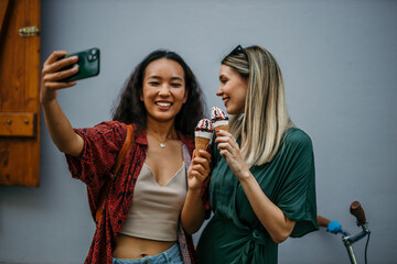two friends, one Chinese and one Caucasian, sipping ice cream amidst the urban hustle on a warm...