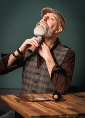 Portrait d'un homme élégant hipster barbier qui rase une belle barbe longue grise avec une tondeuse