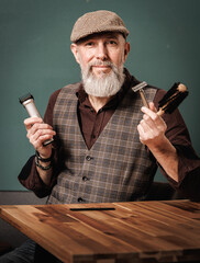 Portrait d'un homme élégant hipster barbier  qui tient un rasoir, un peigne et une tondeuse pour entretenir la barbe