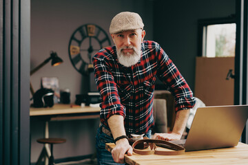 Portrait d'un homme photographe hipster situé dans un studio atelier devant un ordinateur