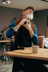 Portrait d'un hipster barbier avec une belle barbe en train de se raser avec une tondeuse dans un atelier magasin