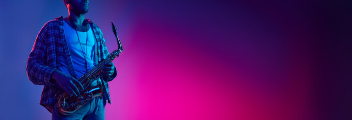 Jazz and blues melodies. African-American man holds saxophone against gradient blue background with...
