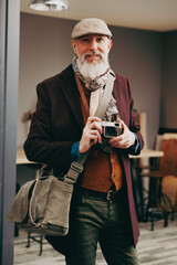 Portrait d'un photographe créatif et original  de type hispter très élégant et stylé avec un manteau un béret et un gilet dans un atelier créatif