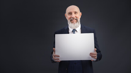 Portrait corporate d'un homme d'affaires souriant en costume et avec barbe qui tient un panneau affiche blanc