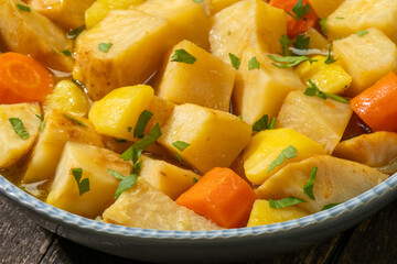 Close-up view of Turkish-style braised celeriac (Zeytinyağlı kereviz) in bowl on rustic wooden table.