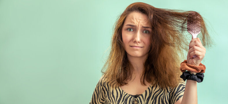 A woman struggling with fizzy hair combing, holding a hair brush. Banner with space for text.