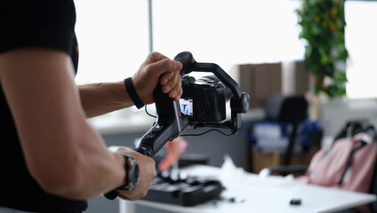 Fototapeta na wymiar Photographer shooting video on camera from tripod closeup. Professional photographic equipment concept
