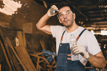 Tired stress carpenter man worker sweating hot workplace hardwork drinking water brake relax...