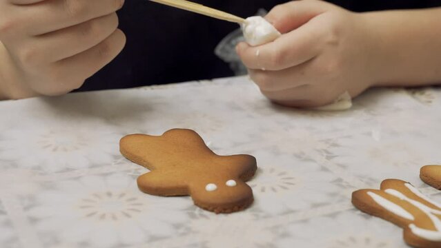 A girl paints gingerbread cookies with sugar cream. Prepares gingerbread cookies. Close-up.