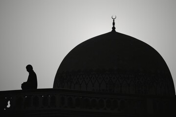 posture of prayer or meditation beside on dome mosque
