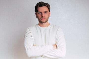 Fototapeta premium Close up portrait of young handsome confident man in casual clothes with crossed and folded arms isolated on gray background