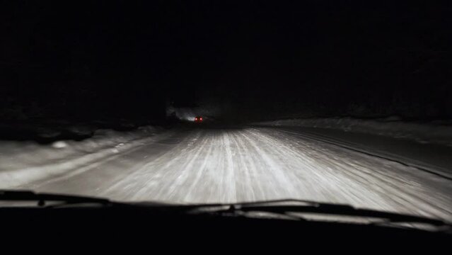 Driving on snow road in forest at night. POV