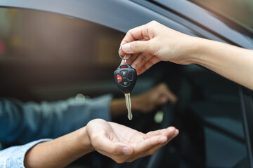 Buy second-hand auto or rent a car concept, Close-up hand of used car agent giving an auto key to client.