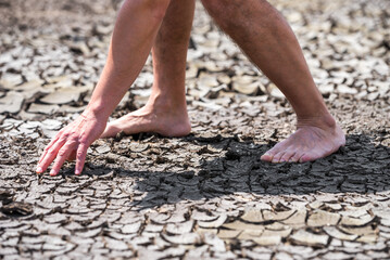 bare feet of a person on dry soil without plants close up