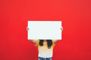 Portrait of a woman holding a blank white sign on a red background