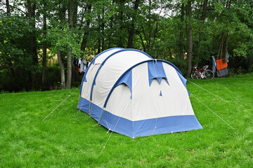 Canvas tunnel tent near a creek on the lawn of the campsite in the Belgian Ardennes