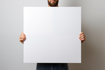 A man holding a white canvas in front of him, used for mockups.