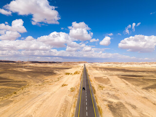 Car zooming by heading north on a Desert highway with cloudy blue sky