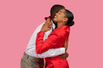 Joyful embrace between black man in white and woman in red