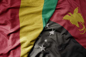 big waving national colorful flag of Papua New Guinea and national flag of guinea .