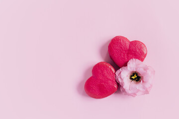 Pink heart shaped french macarons with flower on a pink pastel background. Concept for Valentine's...