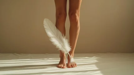 Tapeten Close-up cropped photo of the raised bare feet of a woman holding a feather © Zaleman