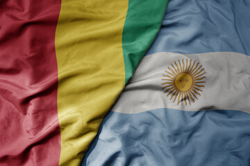 big waving national colorful flag of argentina and national flag of guinea .