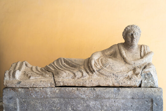 Ancient etruscan statue in stone showing a person laying down on a divan